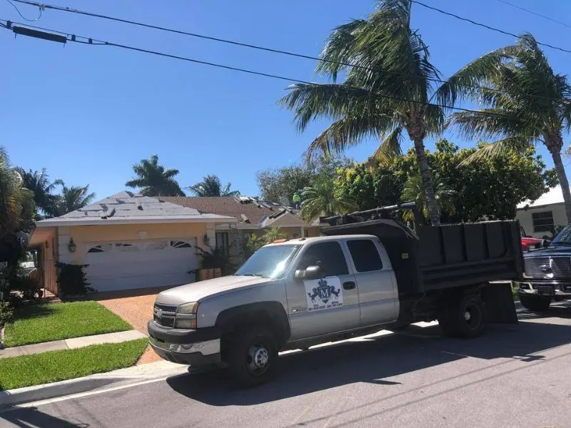 Mendieta Roofing work truck with the crest on the door in front of a home being re-roofed