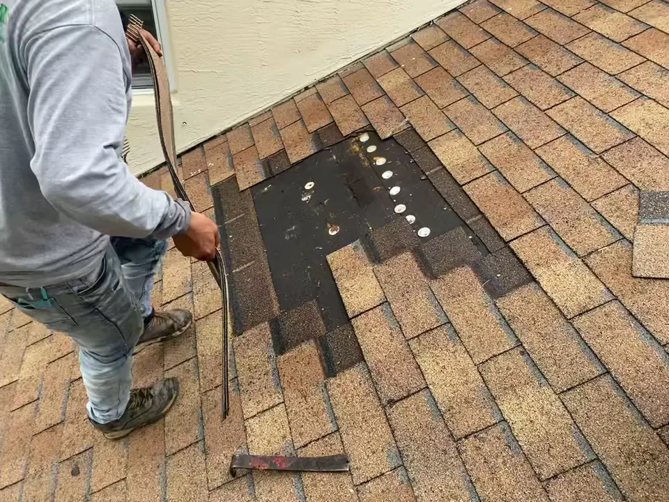 Mendieta roofer pulling up damaged asphalt shingles to patch a section of roof deck